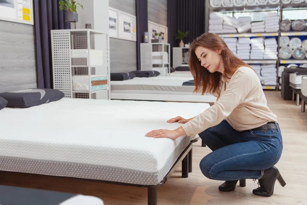 Une femme testant et choisissant son matelas en magasin