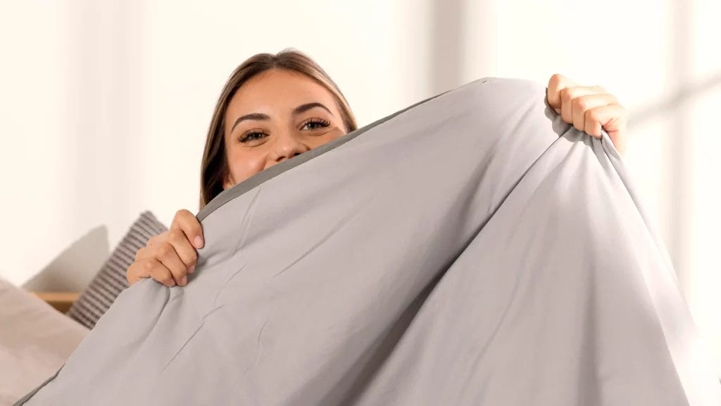 Femme souriante tenant une housse de couette grise.