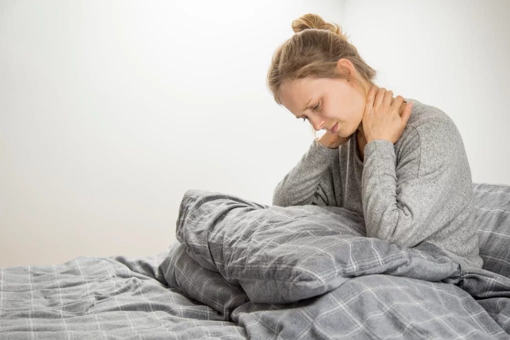 Femme qui a mal au cou dans son lit