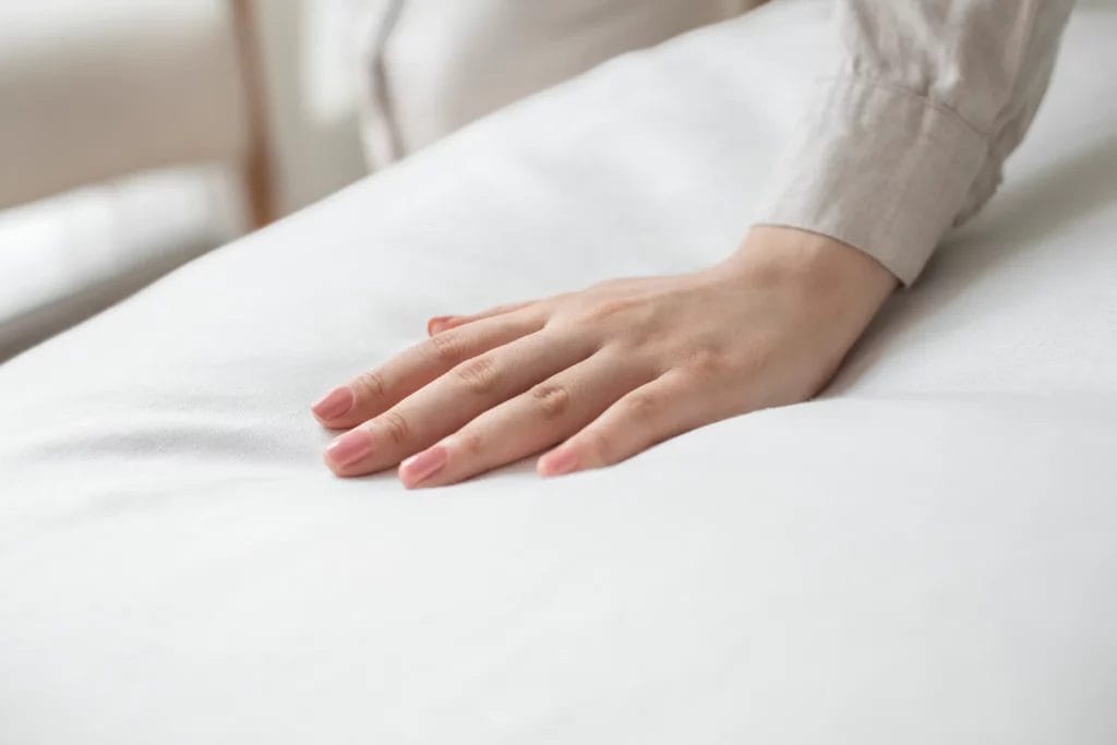 Main posée sur une couette blanche moelleuse