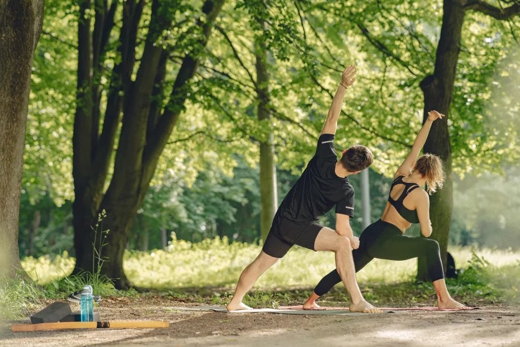 Un couple pratiquant du yoga en tant qu'activité physique dans un parc. 