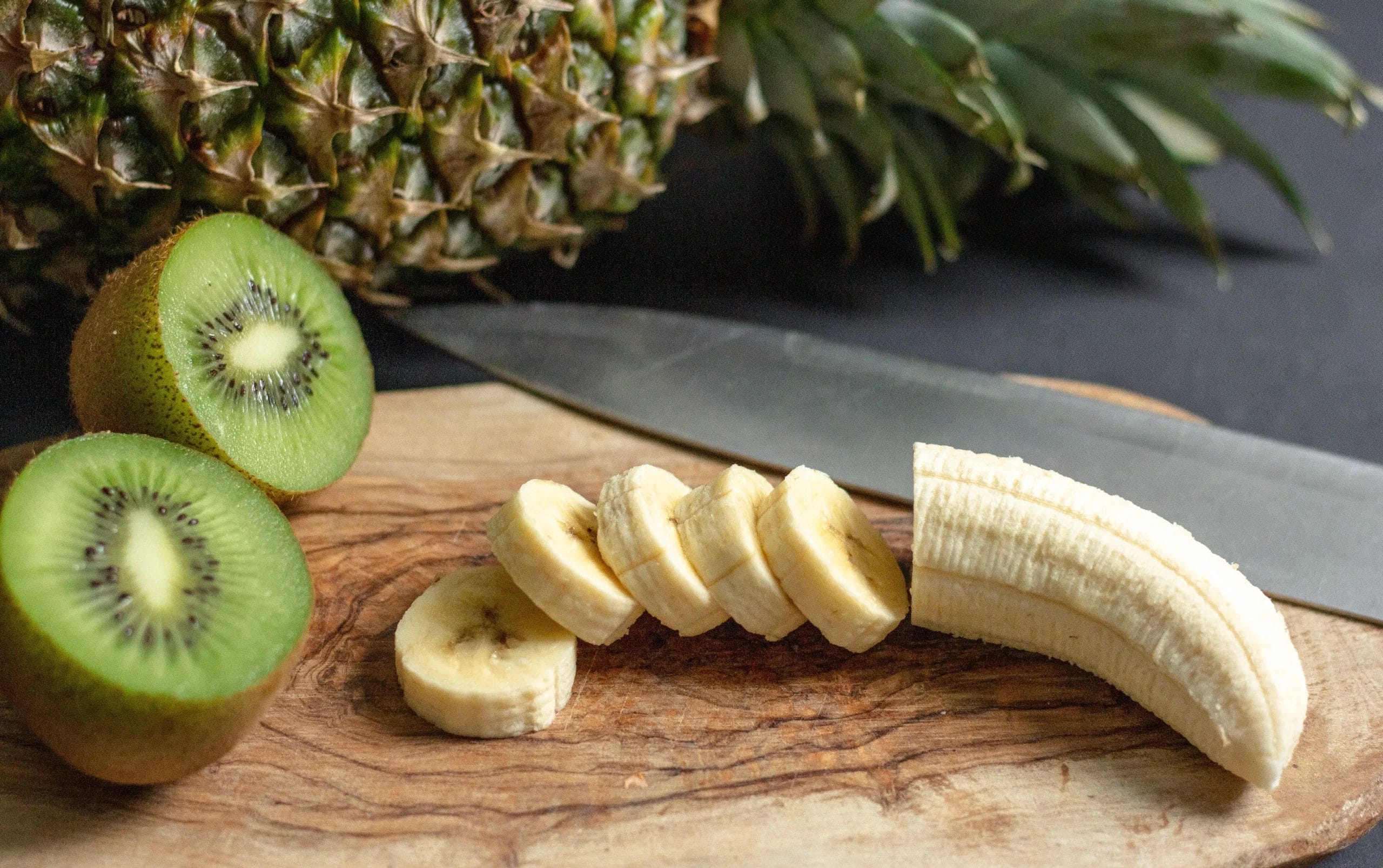 Banane et ananas mis sur une planche à découper l'un à côté de l'autre
