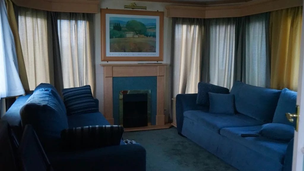 Salon sombre aux rideaux tirés pour bloquer la chaleur et préserver la fraîcheur intérieure pendant l’été.