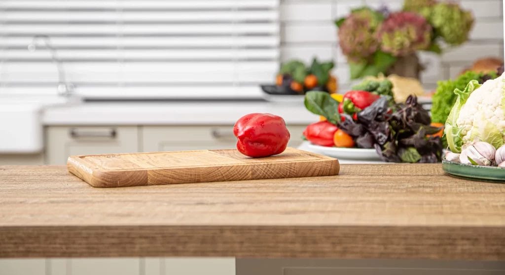 Poivron rouge frais sur une planche en bois dans le contexte d'un intérieur de cuisine.
