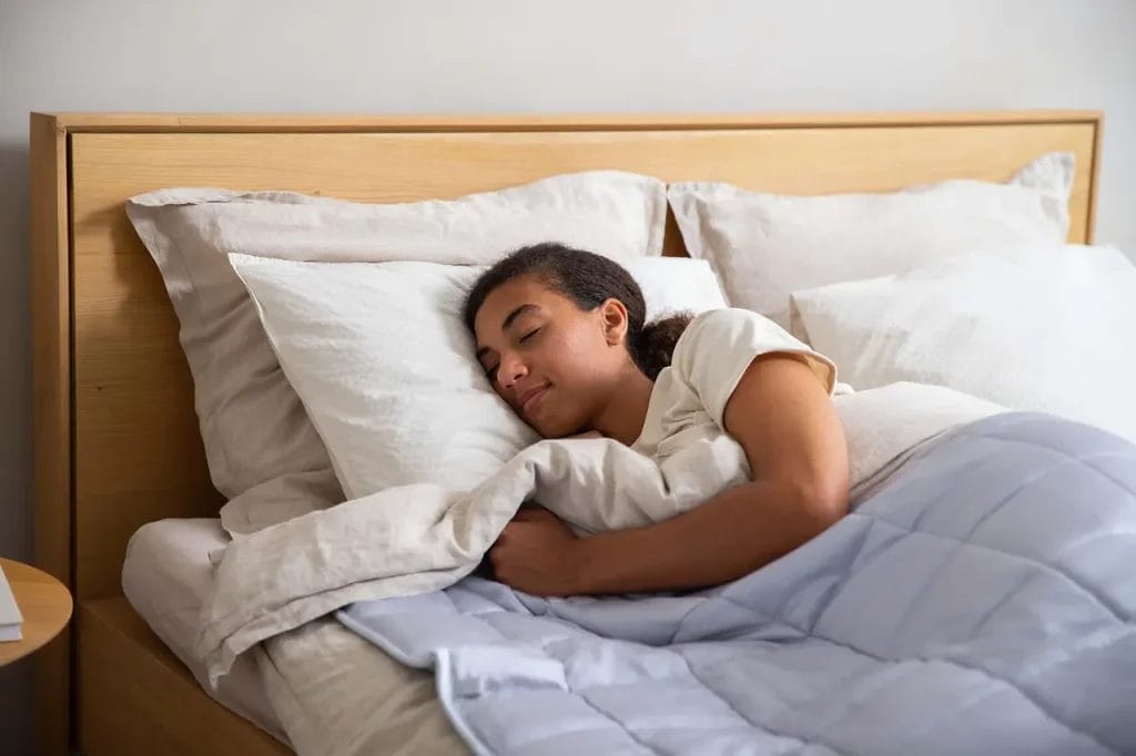 Femme dormant paisiblement sous une couette légère conçue pour rester fraîche pendant les nuits d’été.