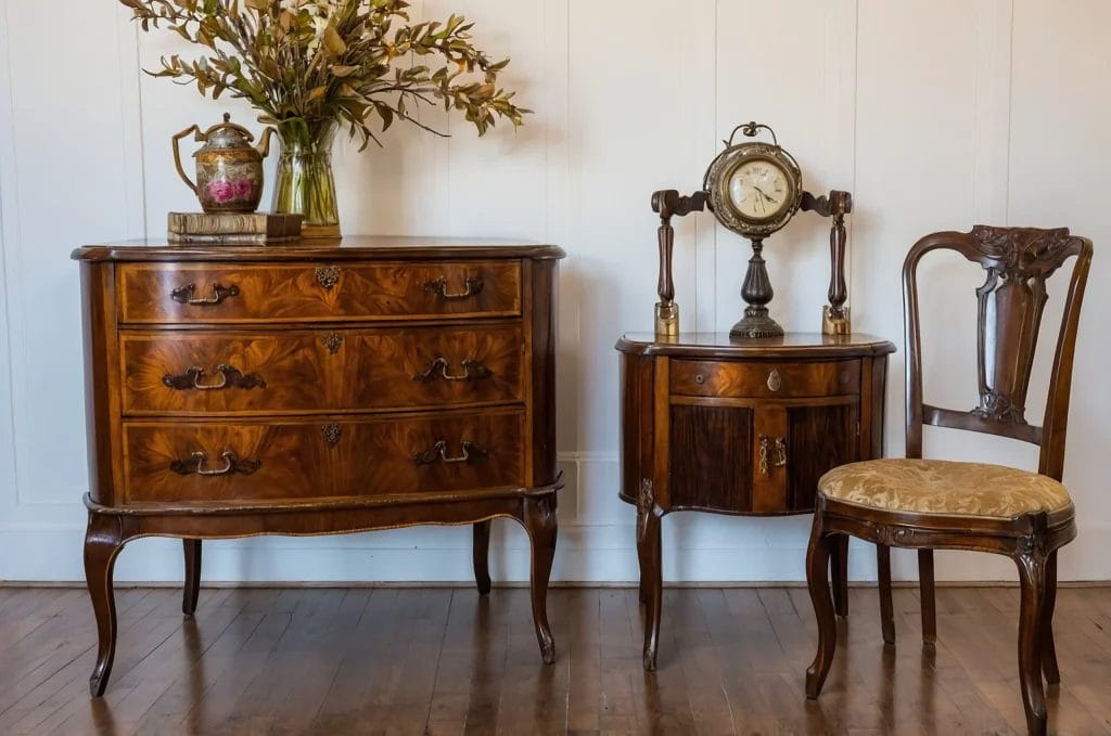 Mobilier ancien en bois avec commode, table, horloge et chaise.