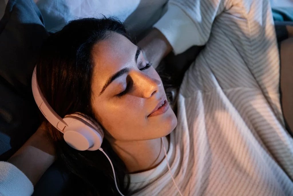 Femme utilisant des écouteurs pour la musique à la maison dans le lit
